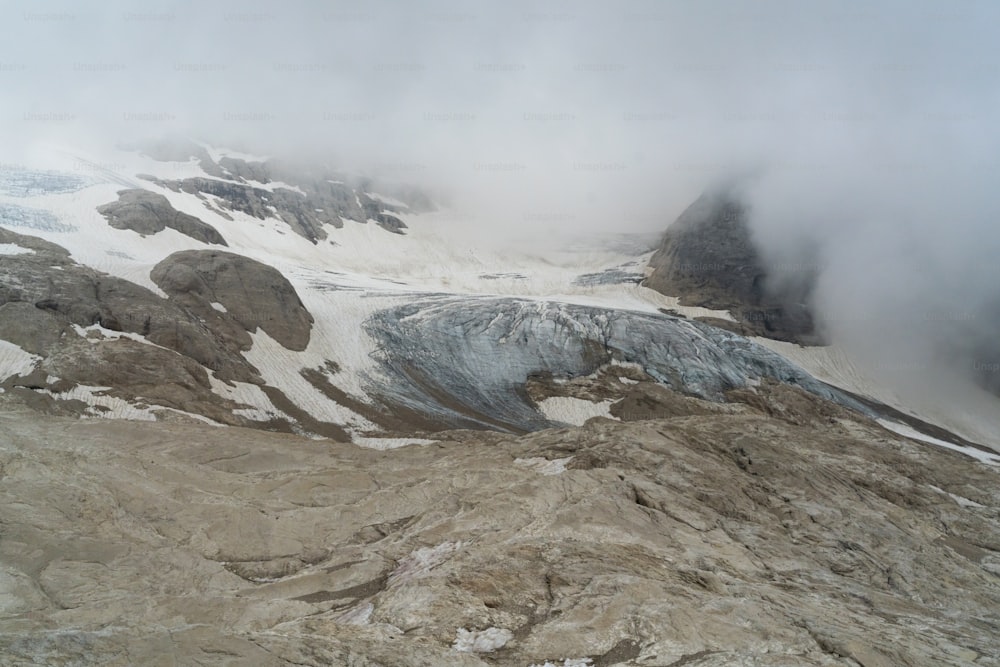 a mountain covered in snow and clouds on a cloudy day