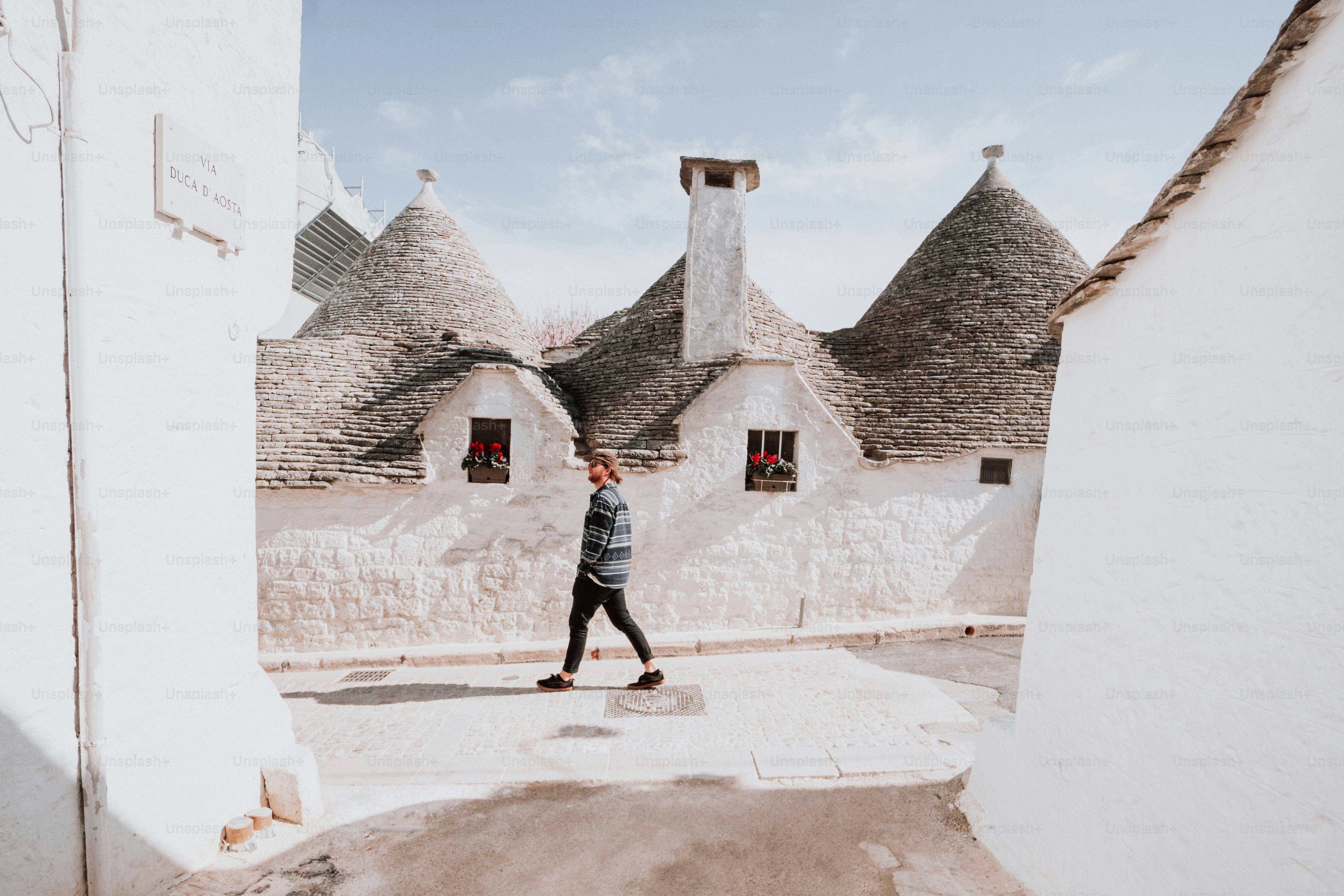 a man walking down a street next to white buildings