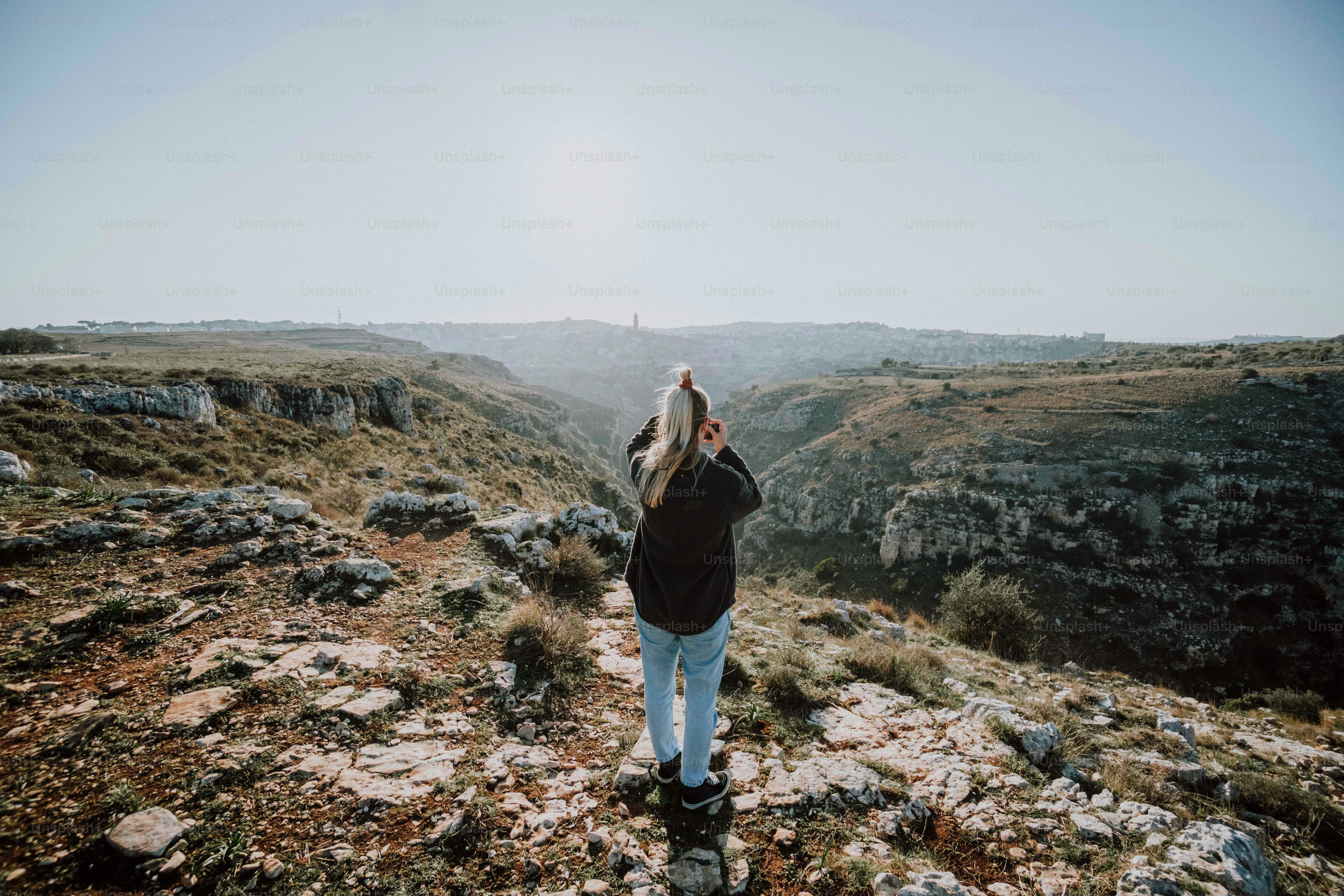 a woman standing on top of a rocky hillside