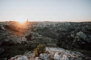 the sun is setting over the rocky terrain