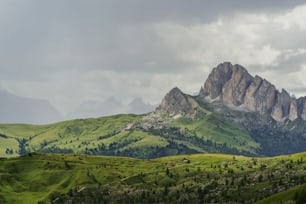 a mountain range with green grass and trees