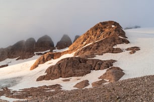 曇り空の下の雪と岩に覆われた山