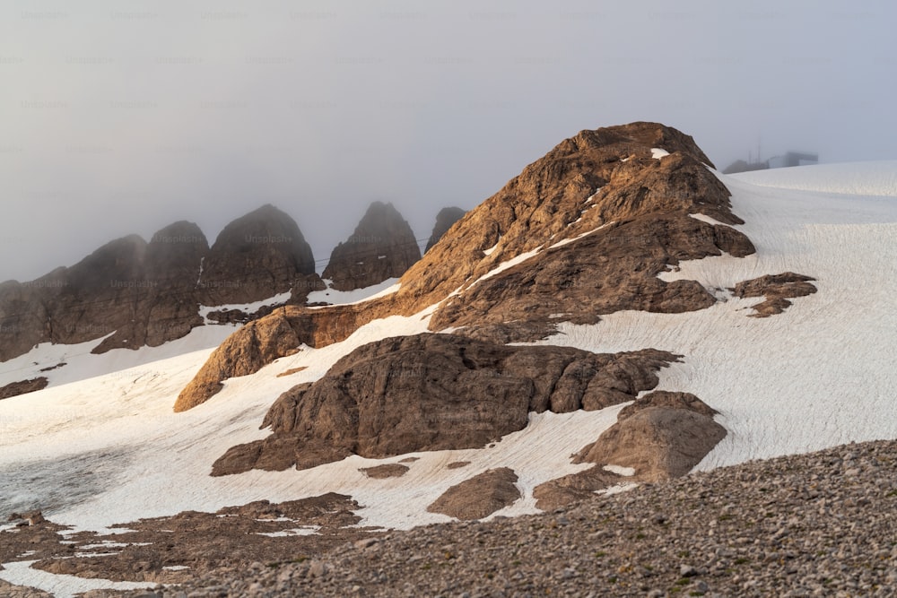 Una montagna coperta di neve e rocce sotto un cielo nuvoloso