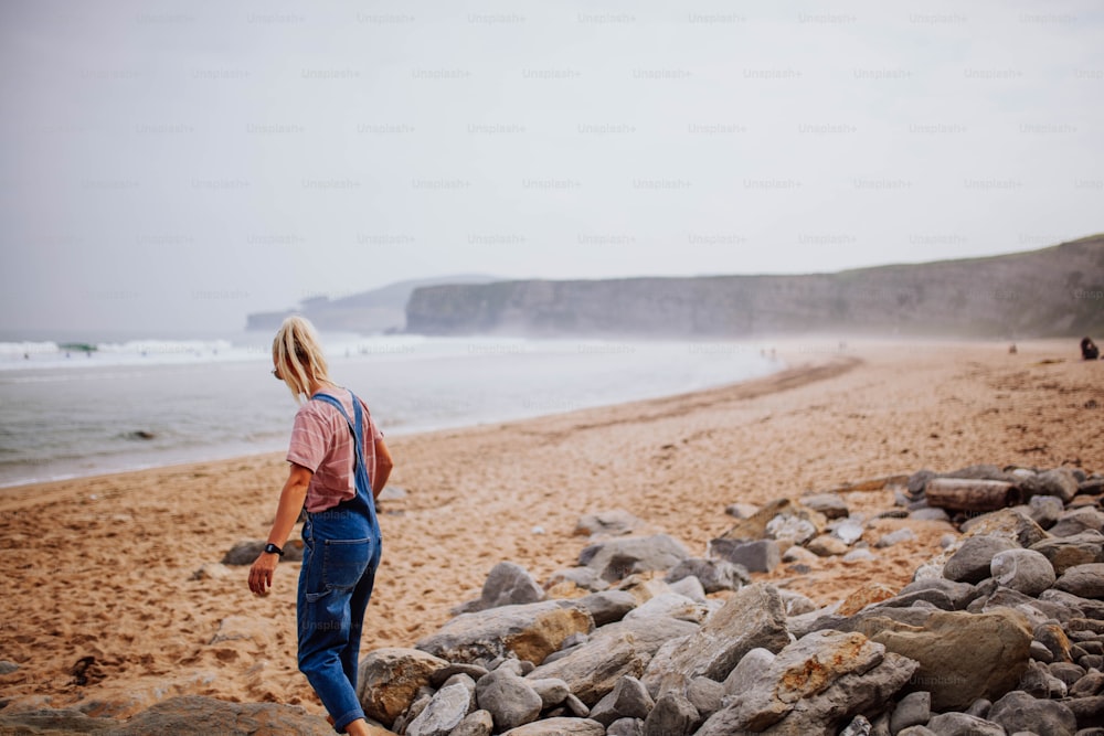 Una mujer parada en la cima de una playa rocosa junto al océano