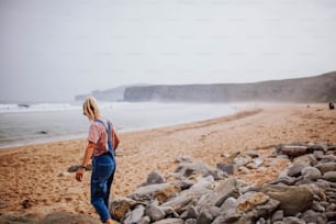 Eine Frau steht auf einem felsigen Strand am Meer