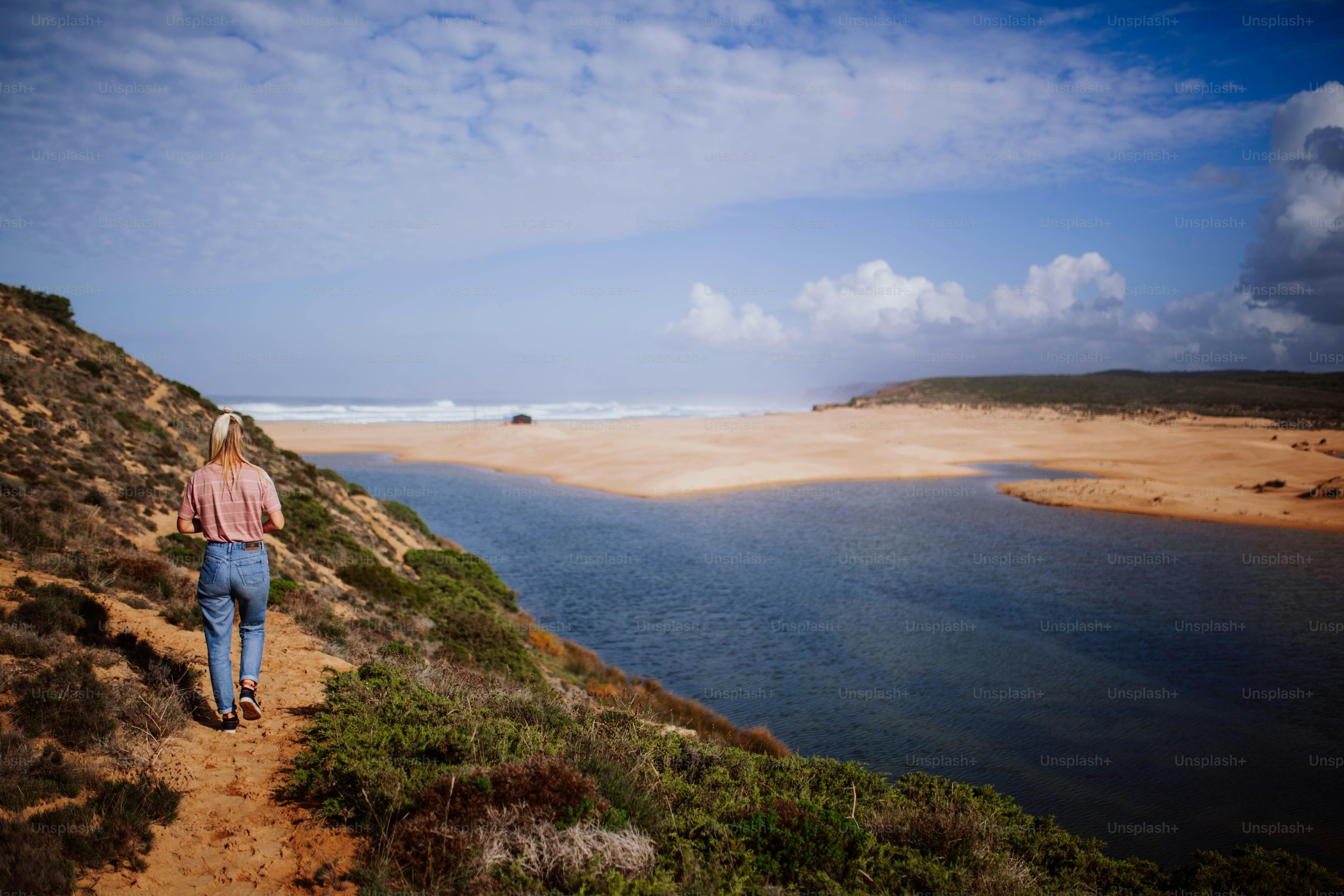a person walking up a hill next to a body of water