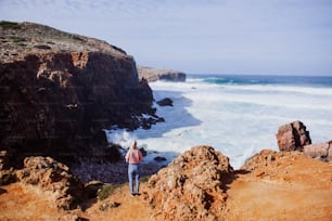 a man standing on top of a cliff near the ocean