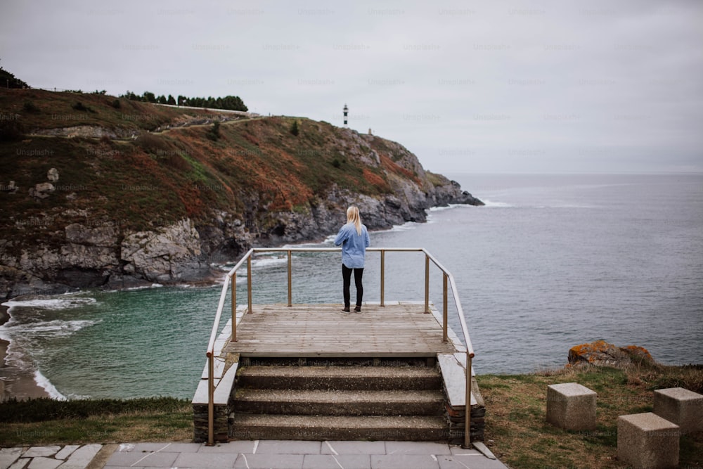 a woman standing on a set of stairs overlooking the ocean