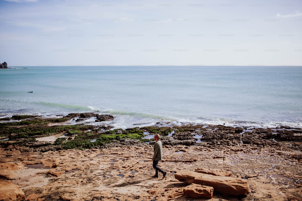 Un uomo in piedi sulla cima di una spiaggia sabbiosa vicino all'oceano