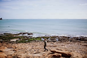 Un homme debout au sommet d’une plage de sable au bord de l’océan