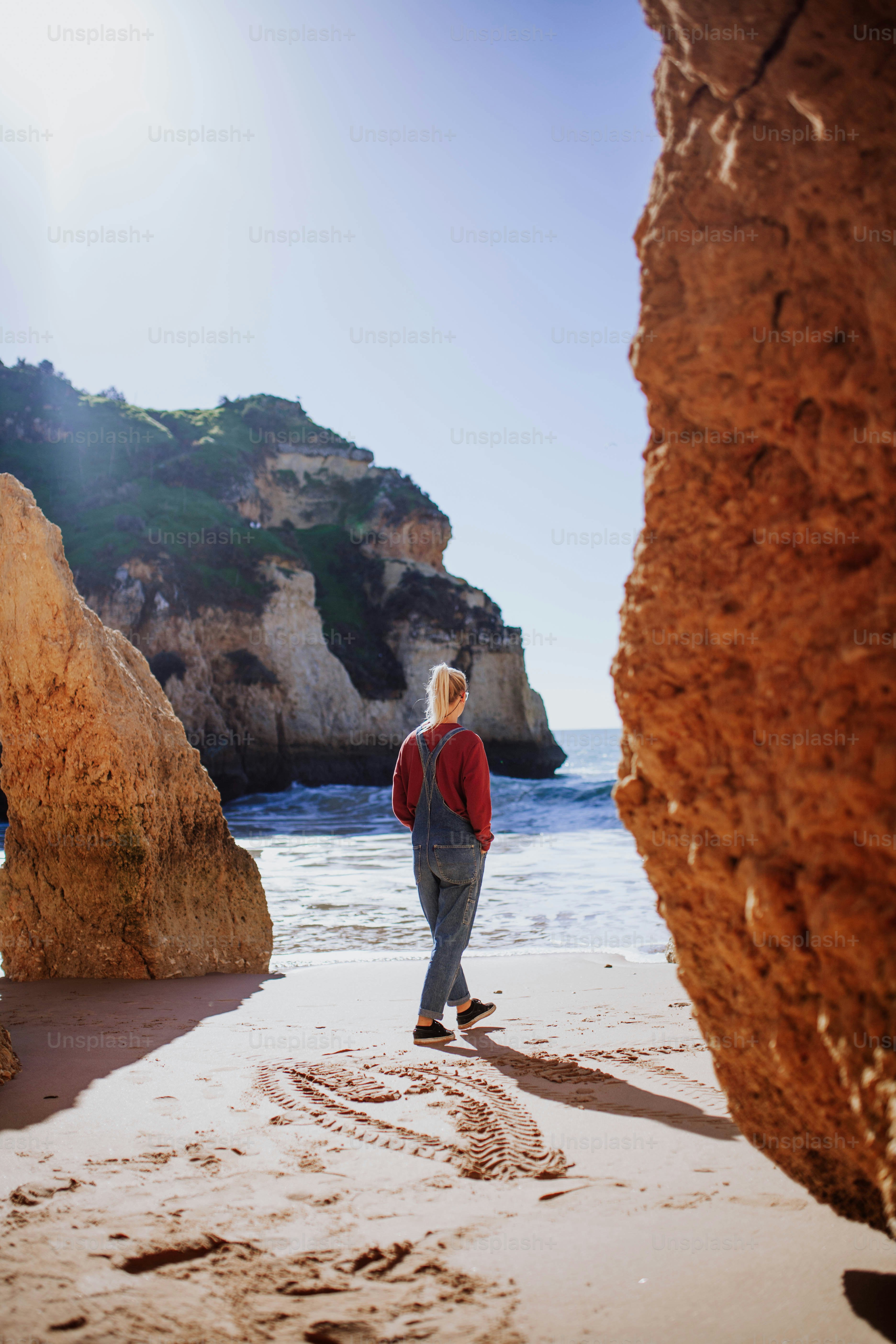 a woman standing on top of a sandy beach