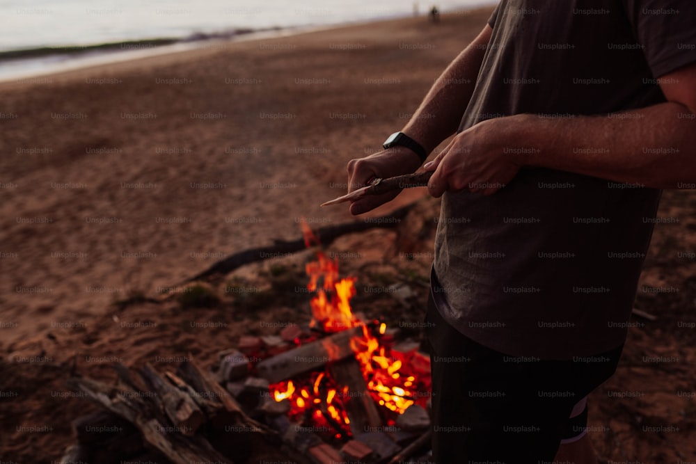 a man standing in front of a fire on a beach