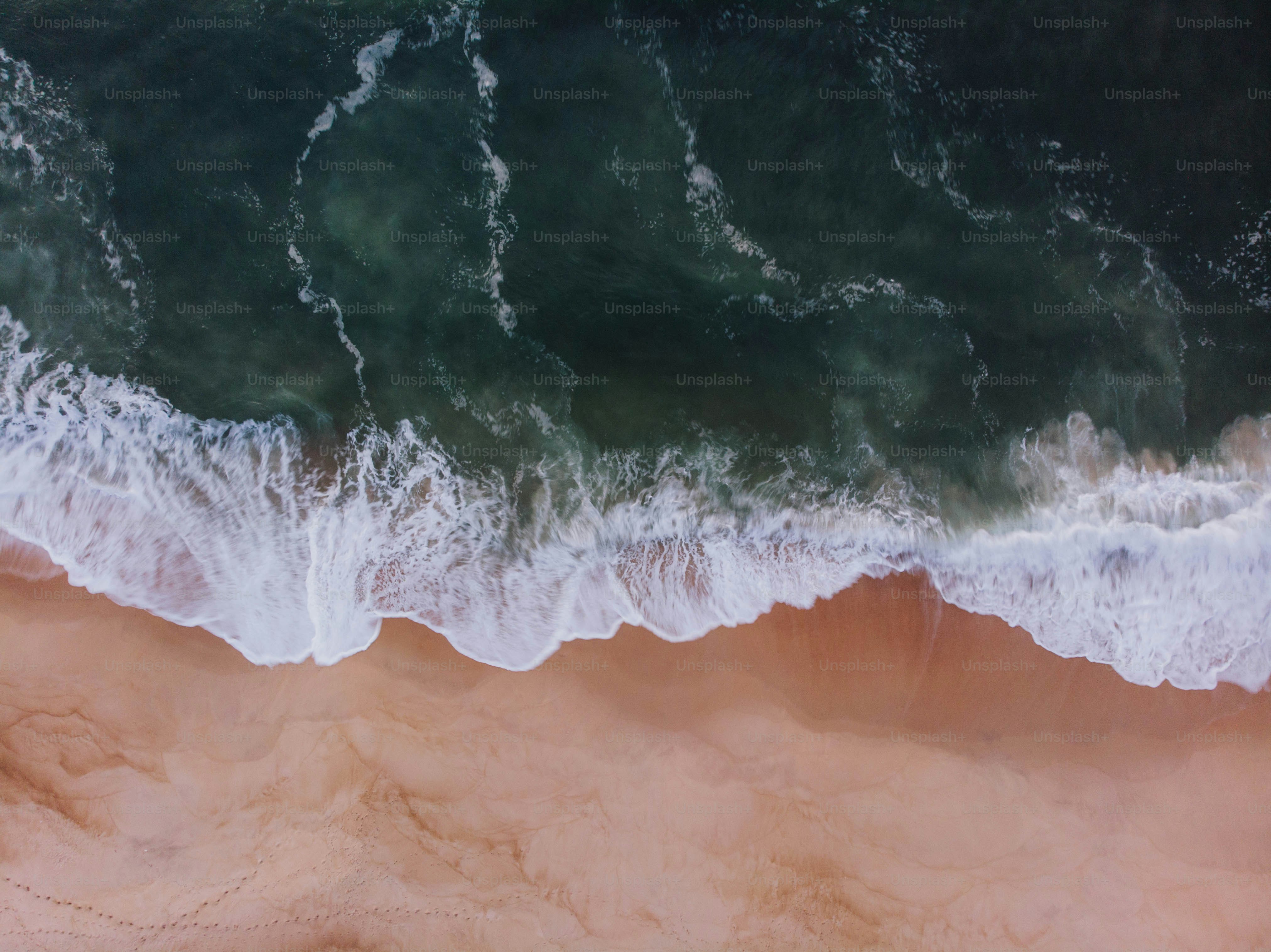 an aerial view of a sandy beach with waves