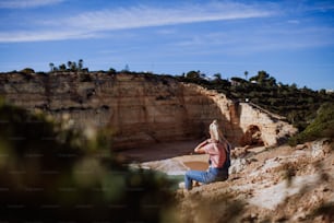 a woman sitting on a cliff overlooking a body of water