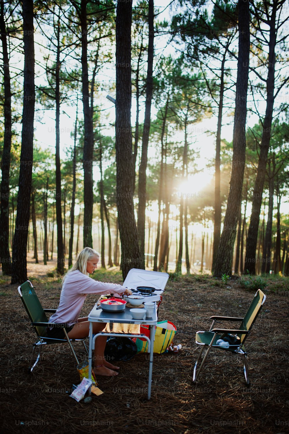 a woman sitting at a picnic table in the woods