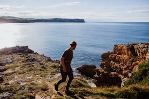 a man standing on top of a cliff next to the ocean