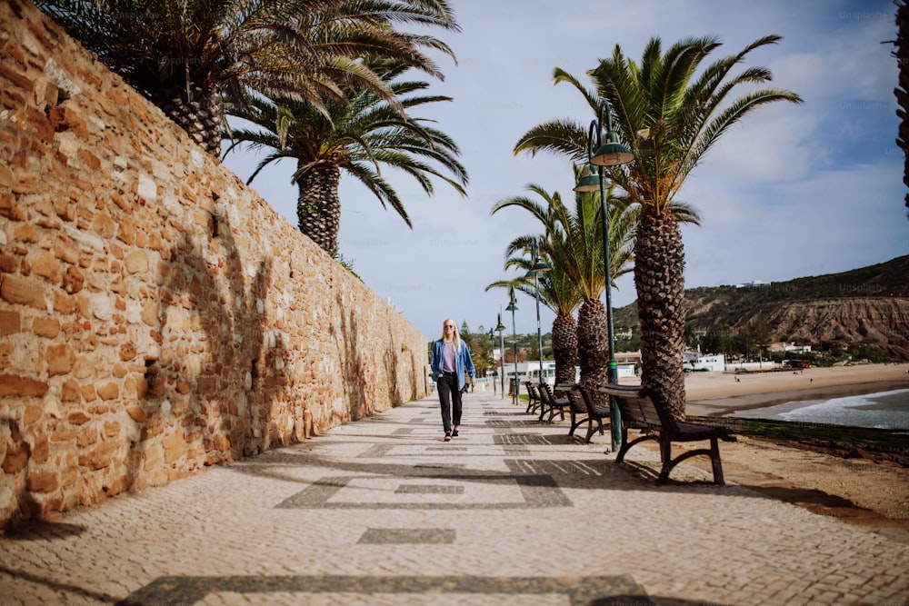 Ein Mann geht neben Palmen einen Bürgersteig entlang