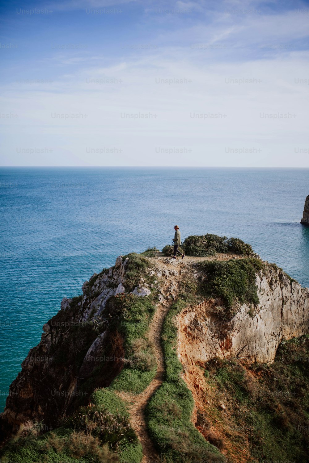 a person standing on top of a cliff near the ocean