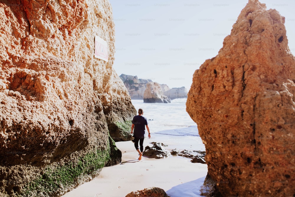 um homem andando ao longo de uma praia ao lado do oceano