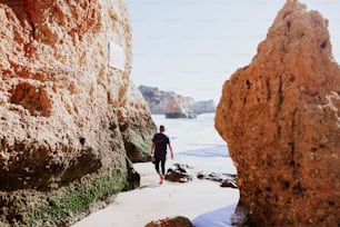 a man walking along a beach next to the ocean