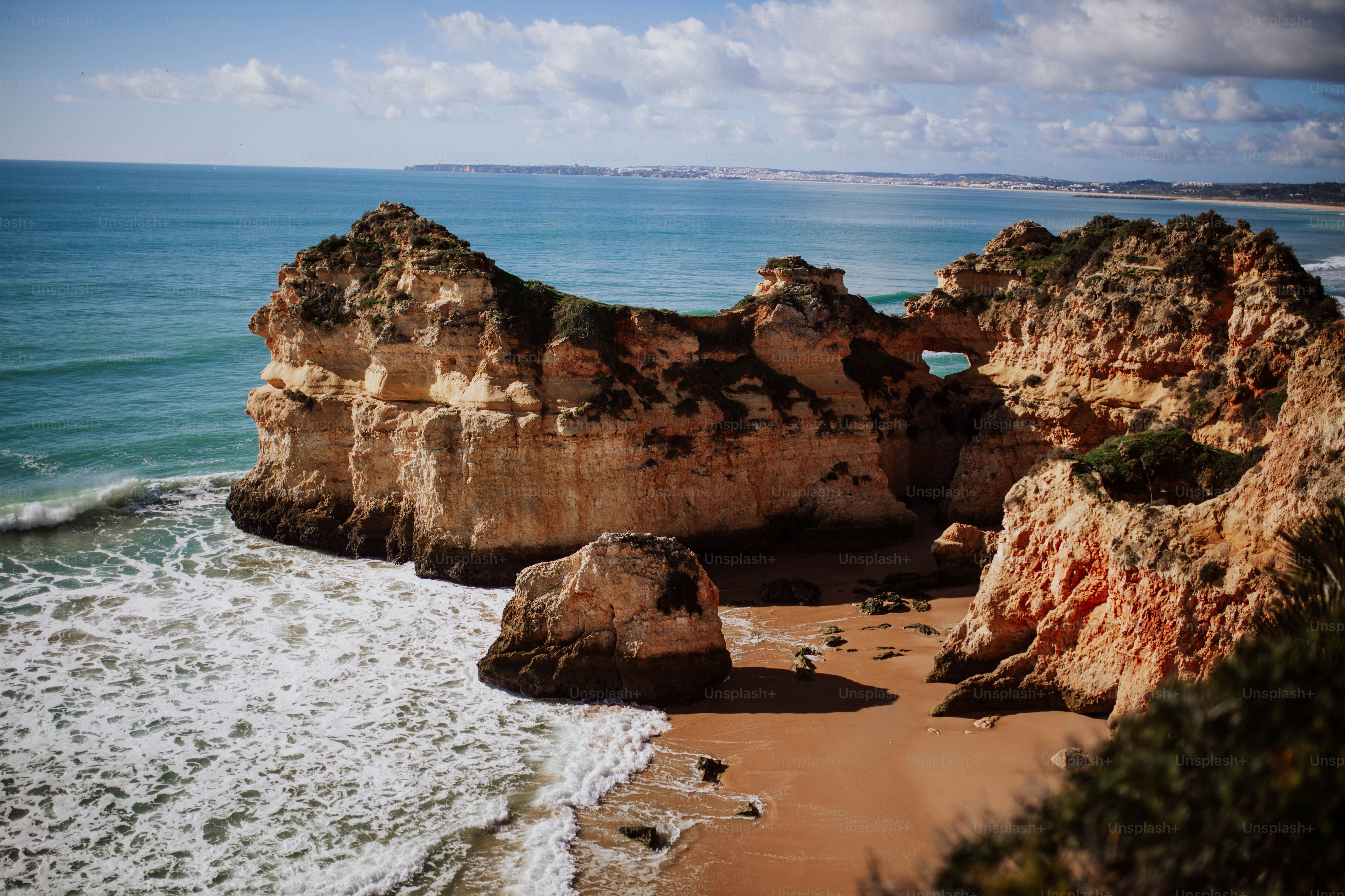 a sandy beach next to a rocky cliff