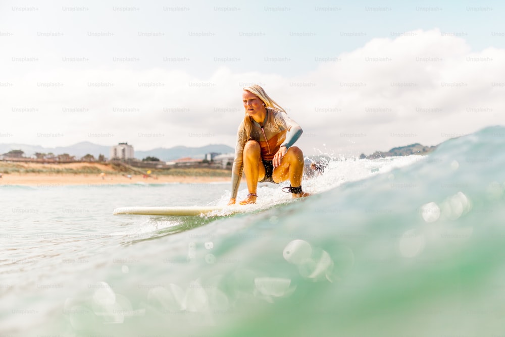 uma mulher que monta uma prancha de surf em cima de uma onda