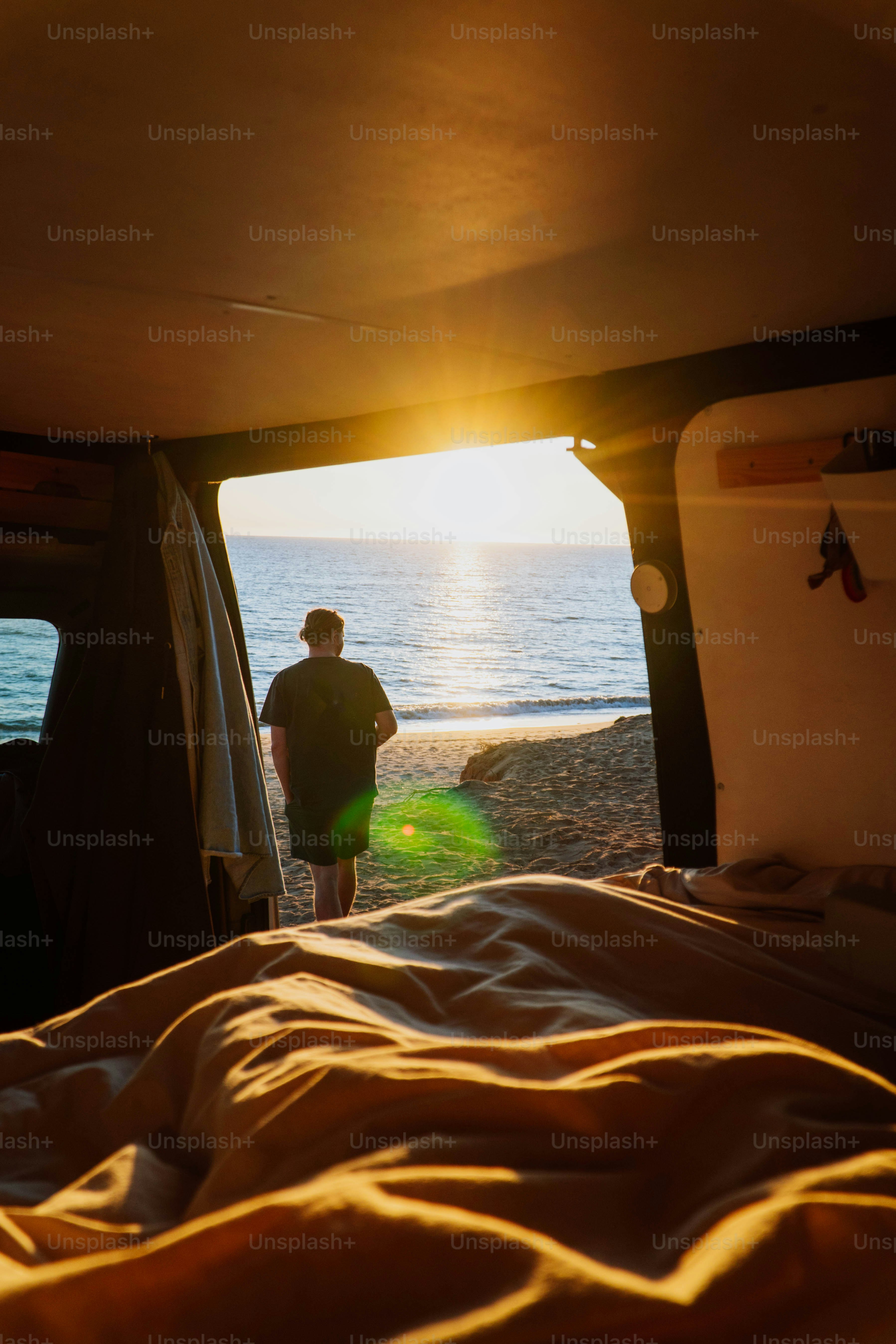 a man standing in the back of a truck next to the ocean