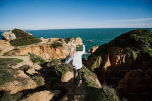 a woman standing on top of a cliff next to the ocean