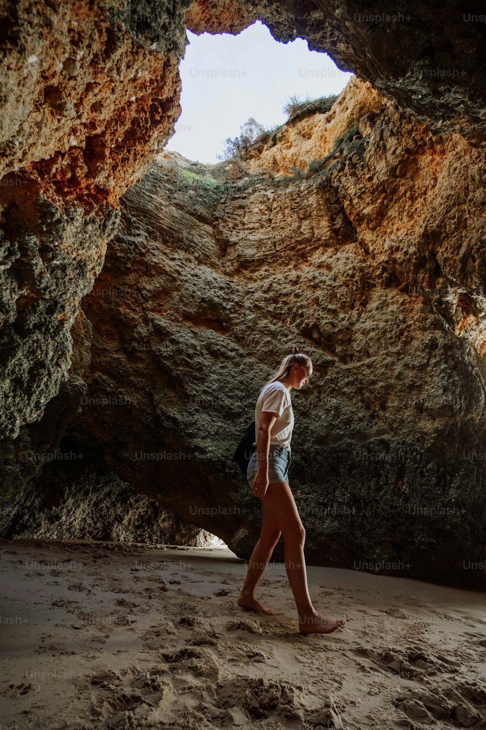 Una donna che cammina attraverso una grotta su una spiaggia