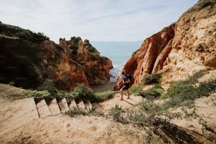 a man hiking up a steep hill next to the ocean