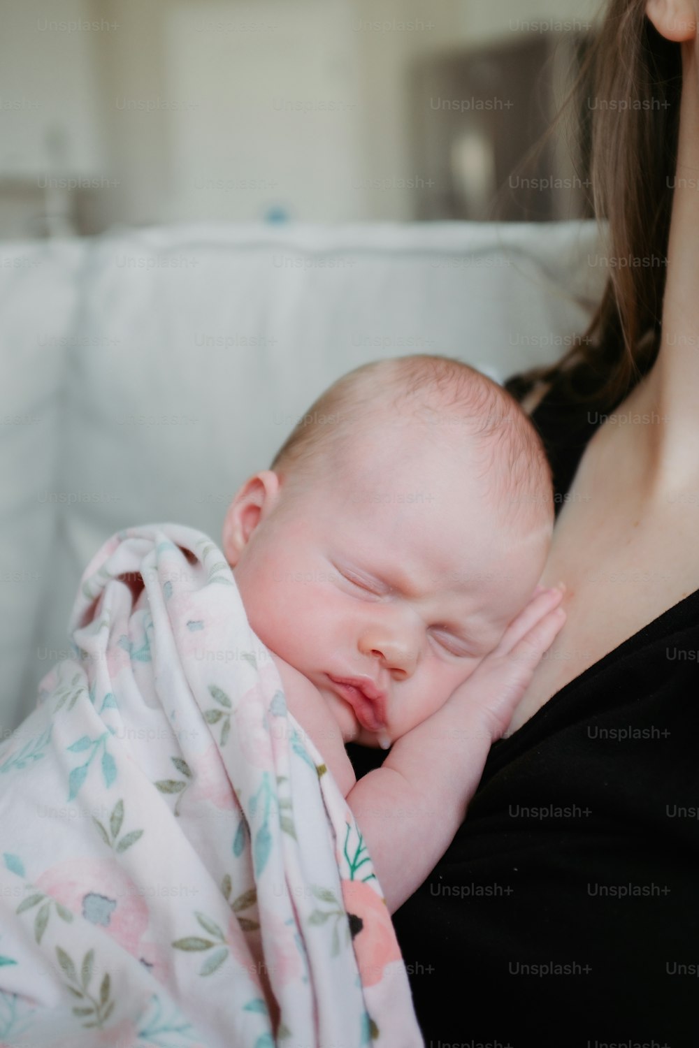 Une femme tenant un bébé endormi enveloppé dans une couverture