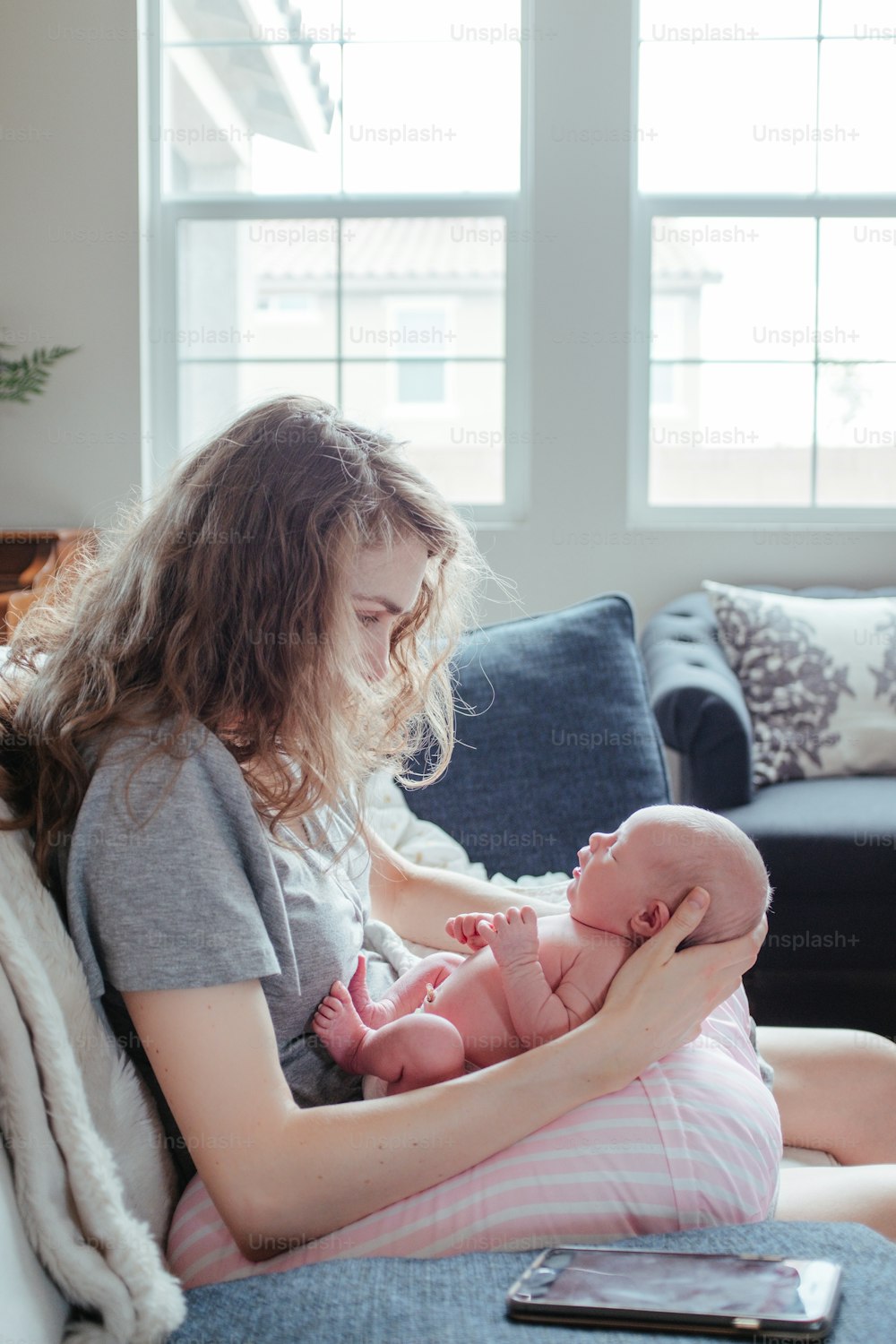 Una mujer sentada en un sofá sosteniendo a un bebé
