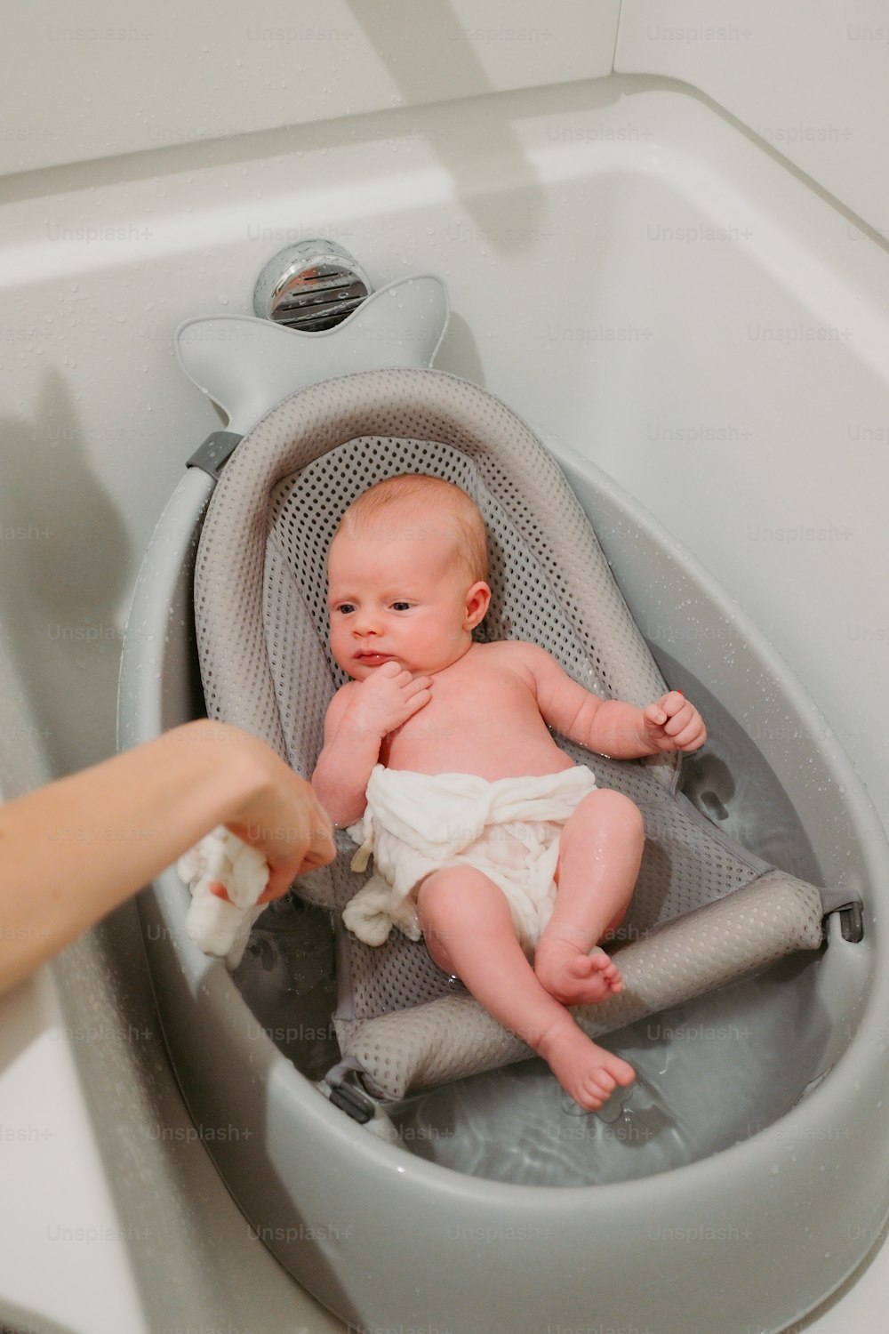a baby in a bathtub being held by a person