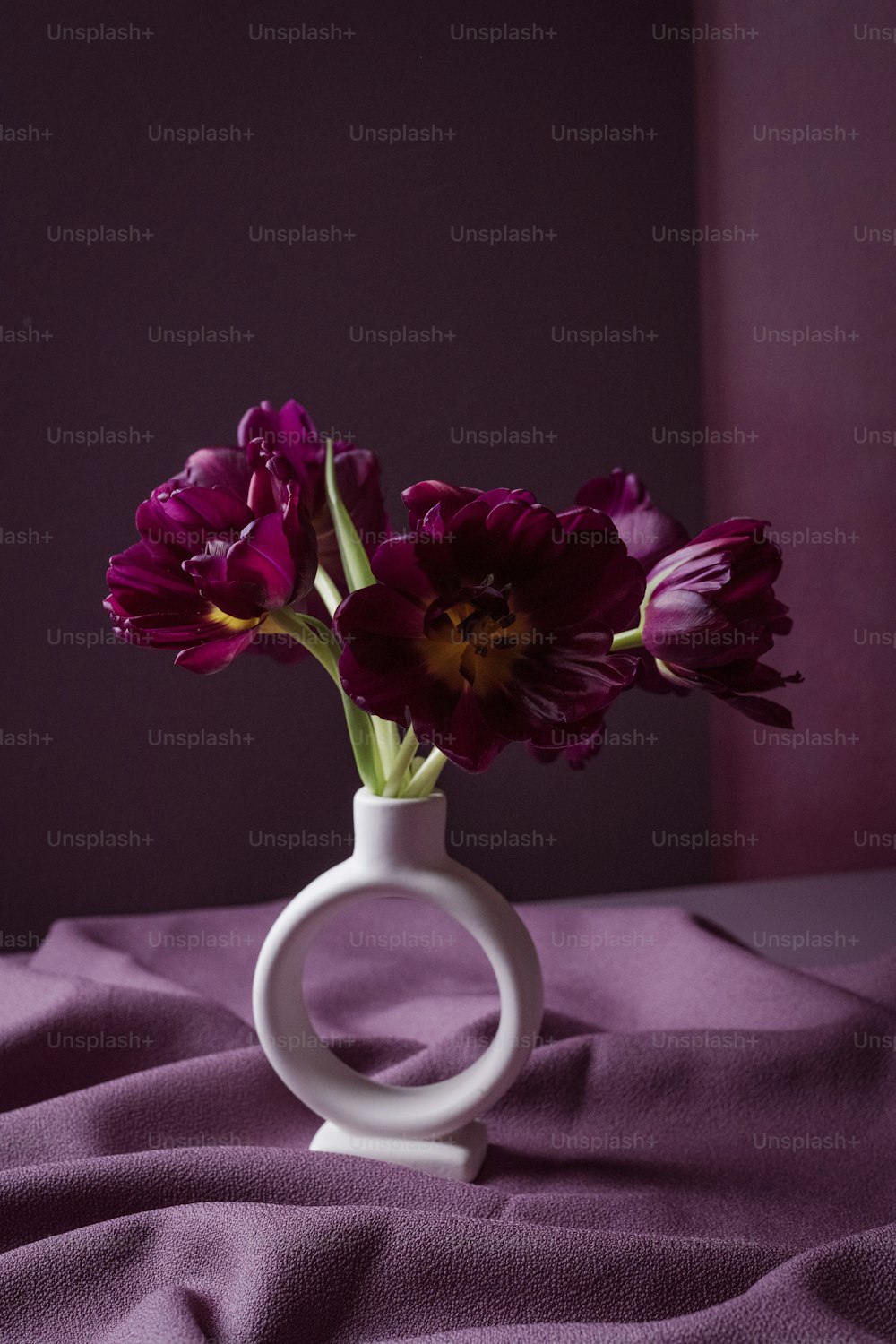 eine weiße Vase mit lila Blumen darin