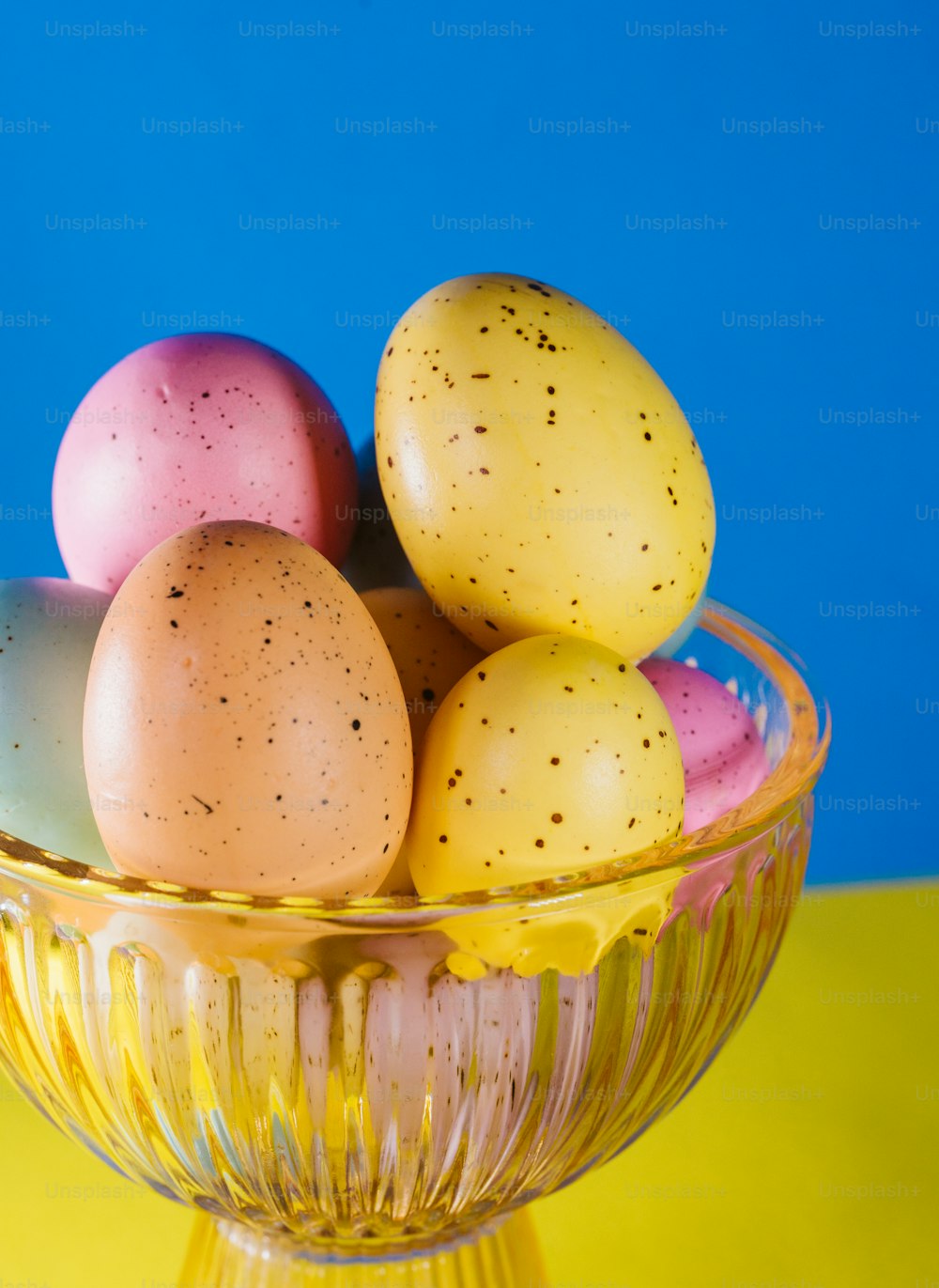 a glass bowl filled with eggs on top of a yellow table