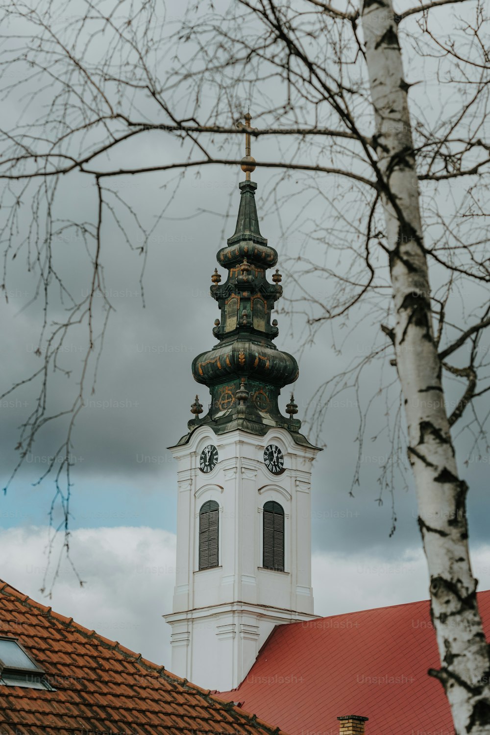 a tall white clock tower sitting next to a tree