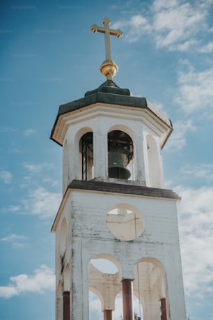 ein weißer Glockenturm der Kirche mit einem Kreuz auf der Spitze