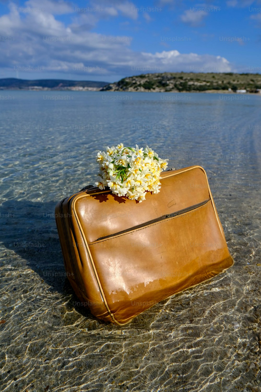 a brown piece of luggage sitting on top of a beach