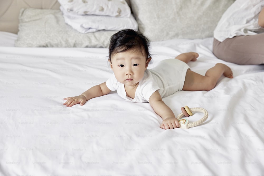 a baby laying on top of a white bed