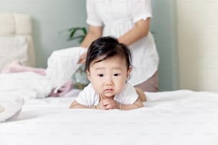 a baby laying on a bed with a woman in the background