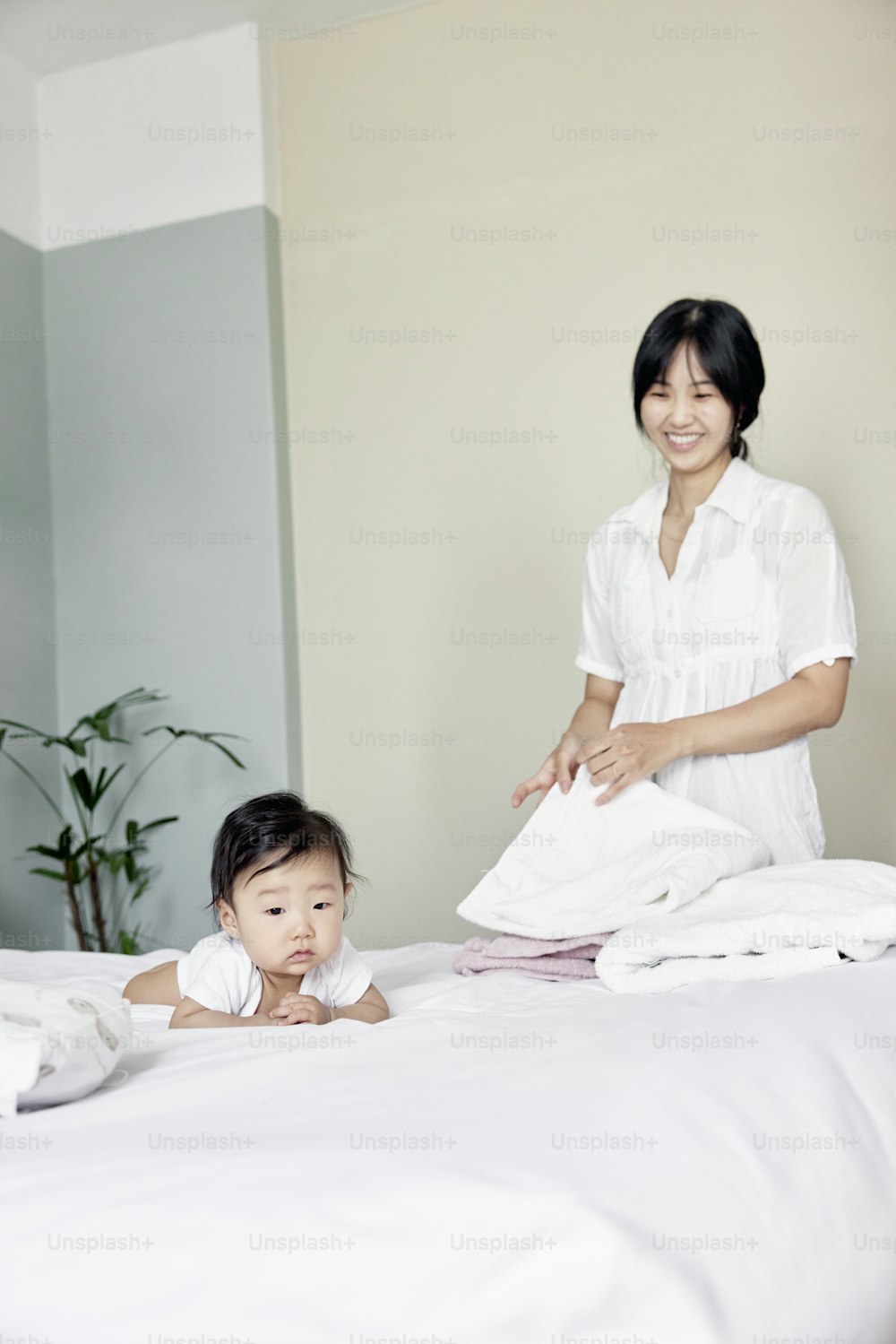a woman standing over a baby laying on top of a bed