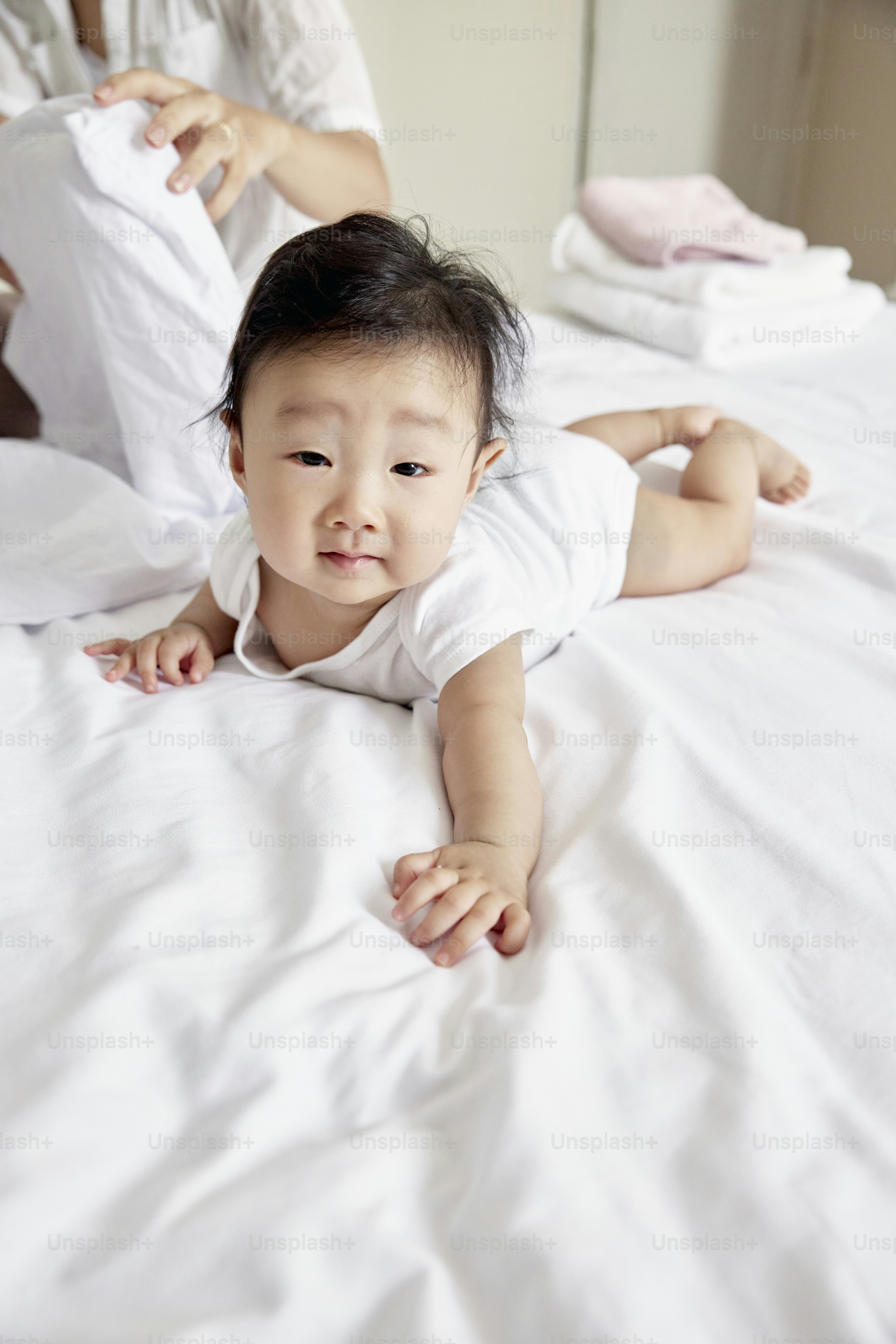 A baby laying on a bed with white sheets photo Kid Image on Unsplash