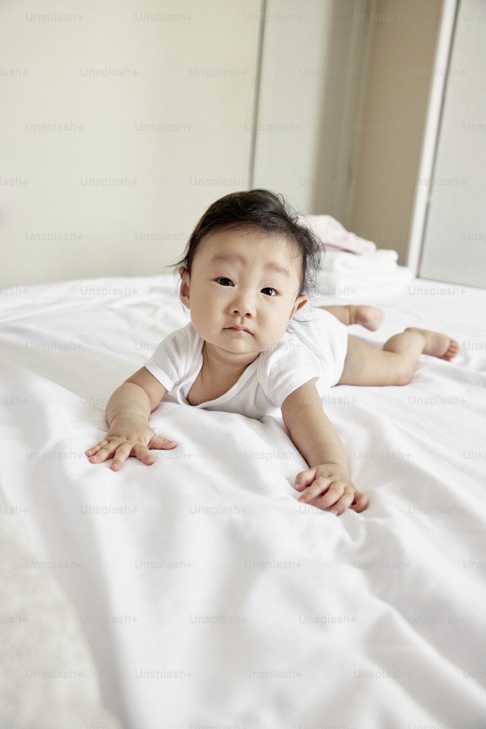 a baby laying on a bed with white sheets