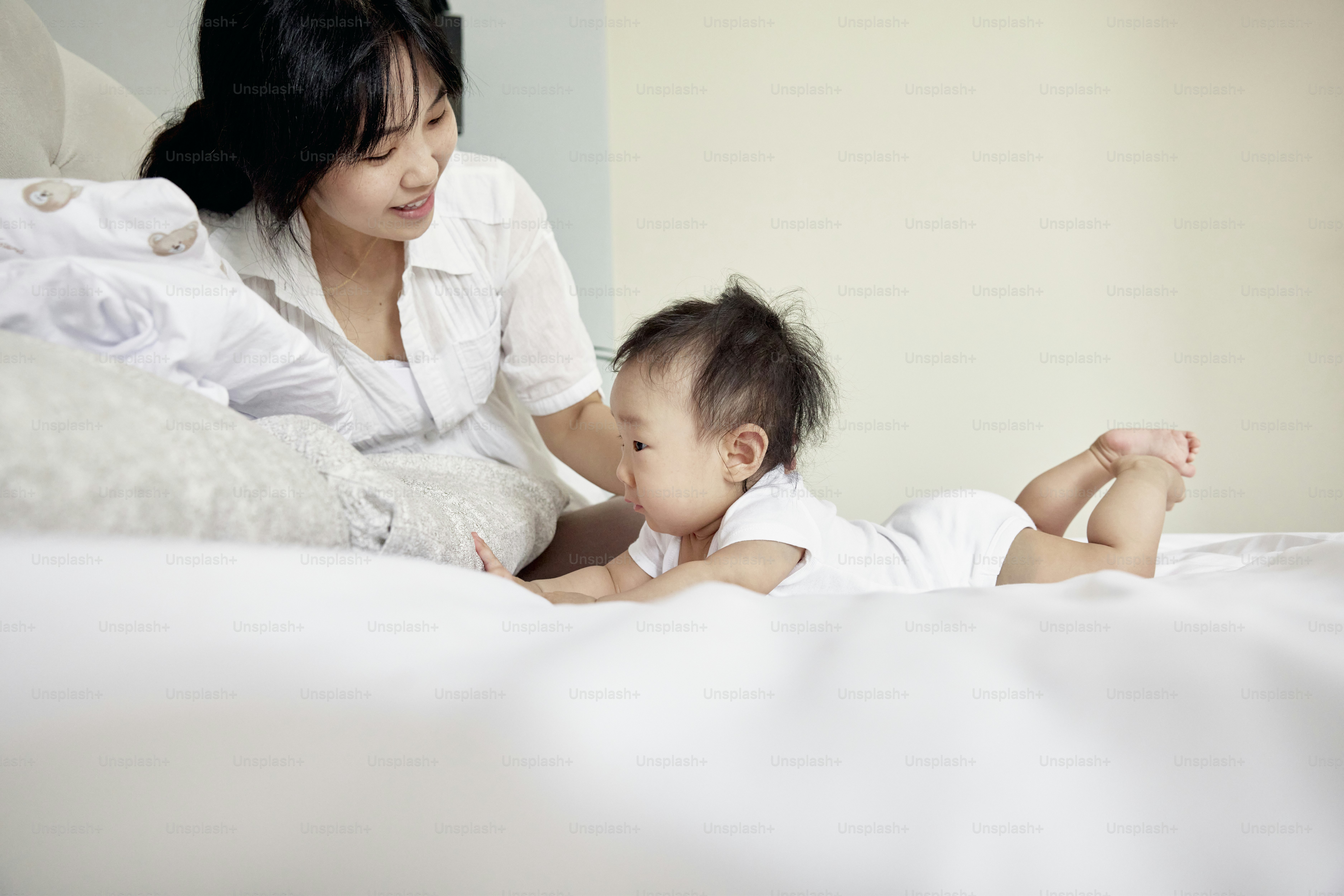 Una mujer y un bebé acostados en una cama foto – Imagen de Familia en ...