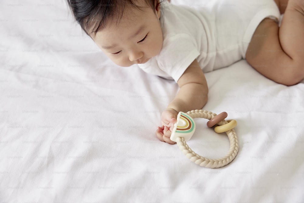 a baby laying on a bed playing with a toy