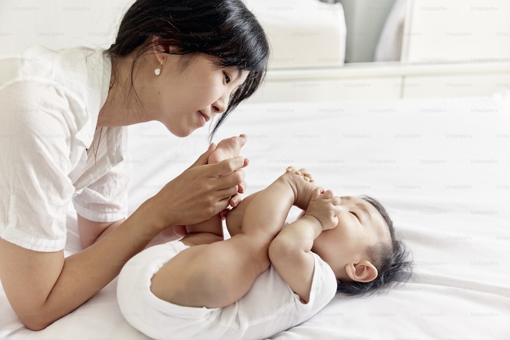 a woman holding a baby on top of a bed