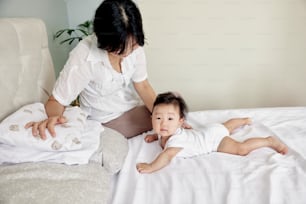 a woman sitting next to a baby on a bed