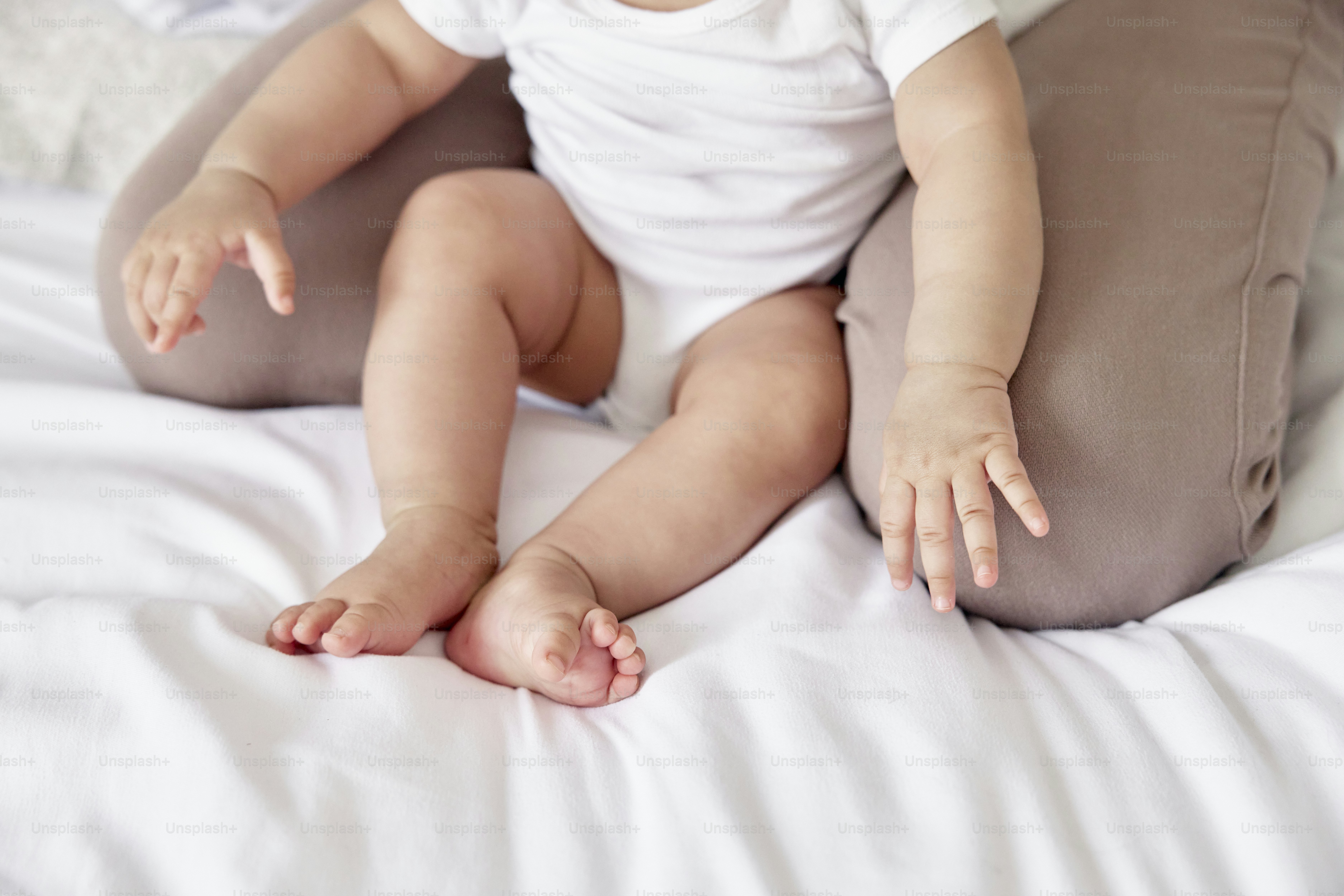 a baby sitting on a pillow on a bed