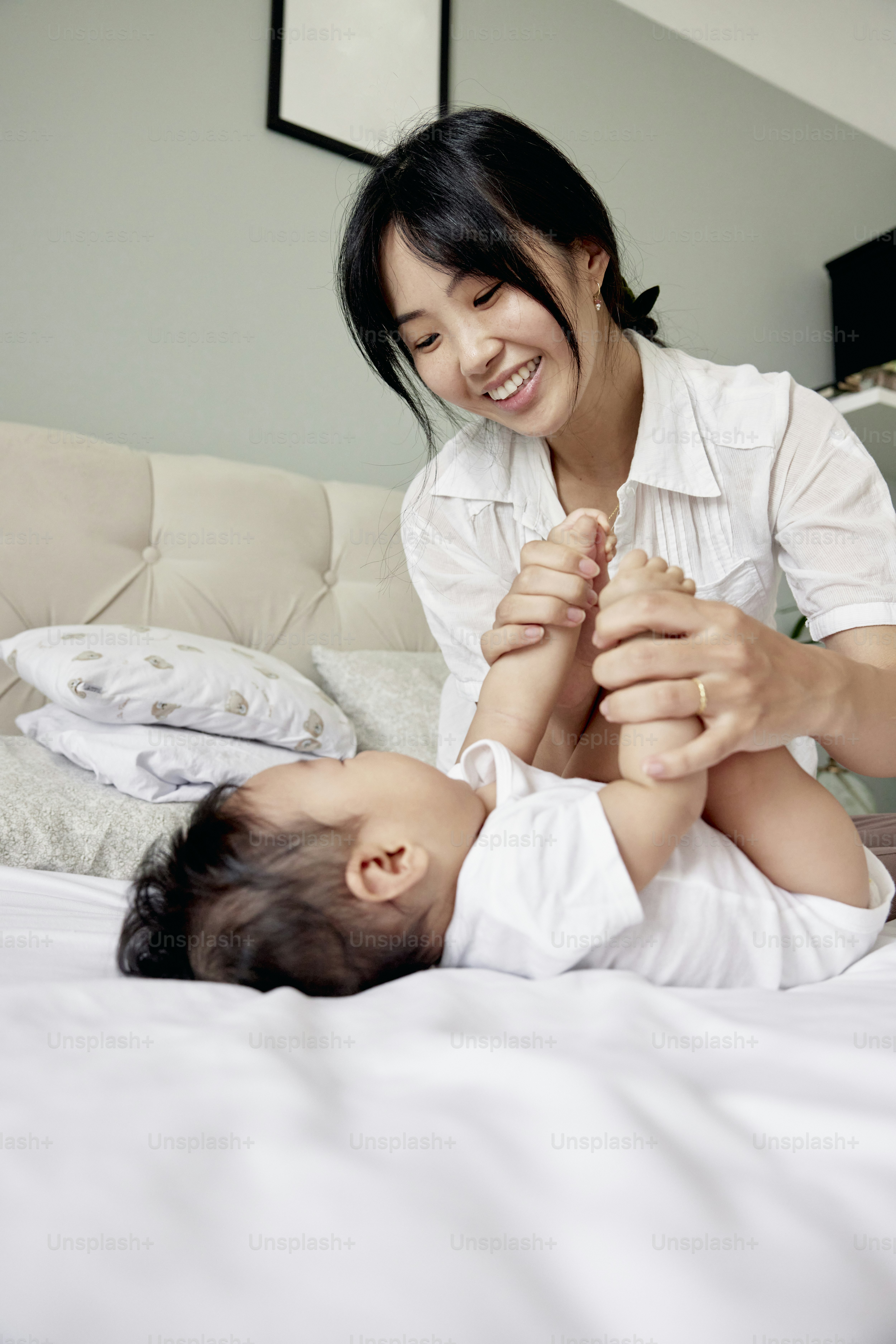 uma mulher que brinca com um bebê em uma cama