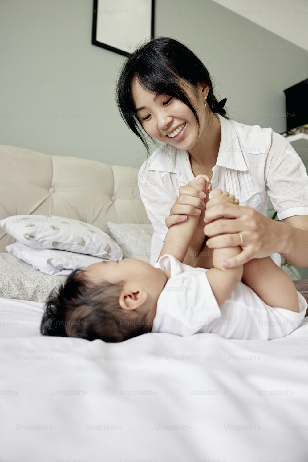a woman playing with a baby on a bed